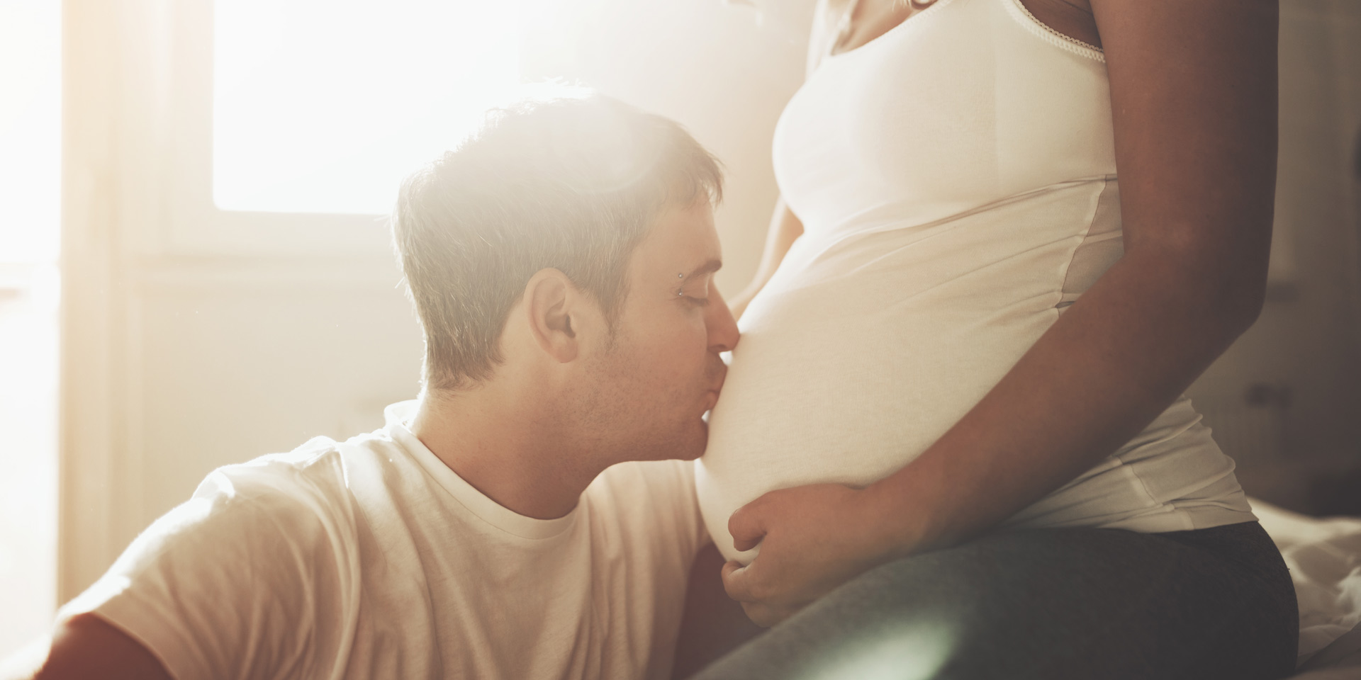 mann küsst bauch einer schwangeren frau. symbolbild familienplanung  geburt