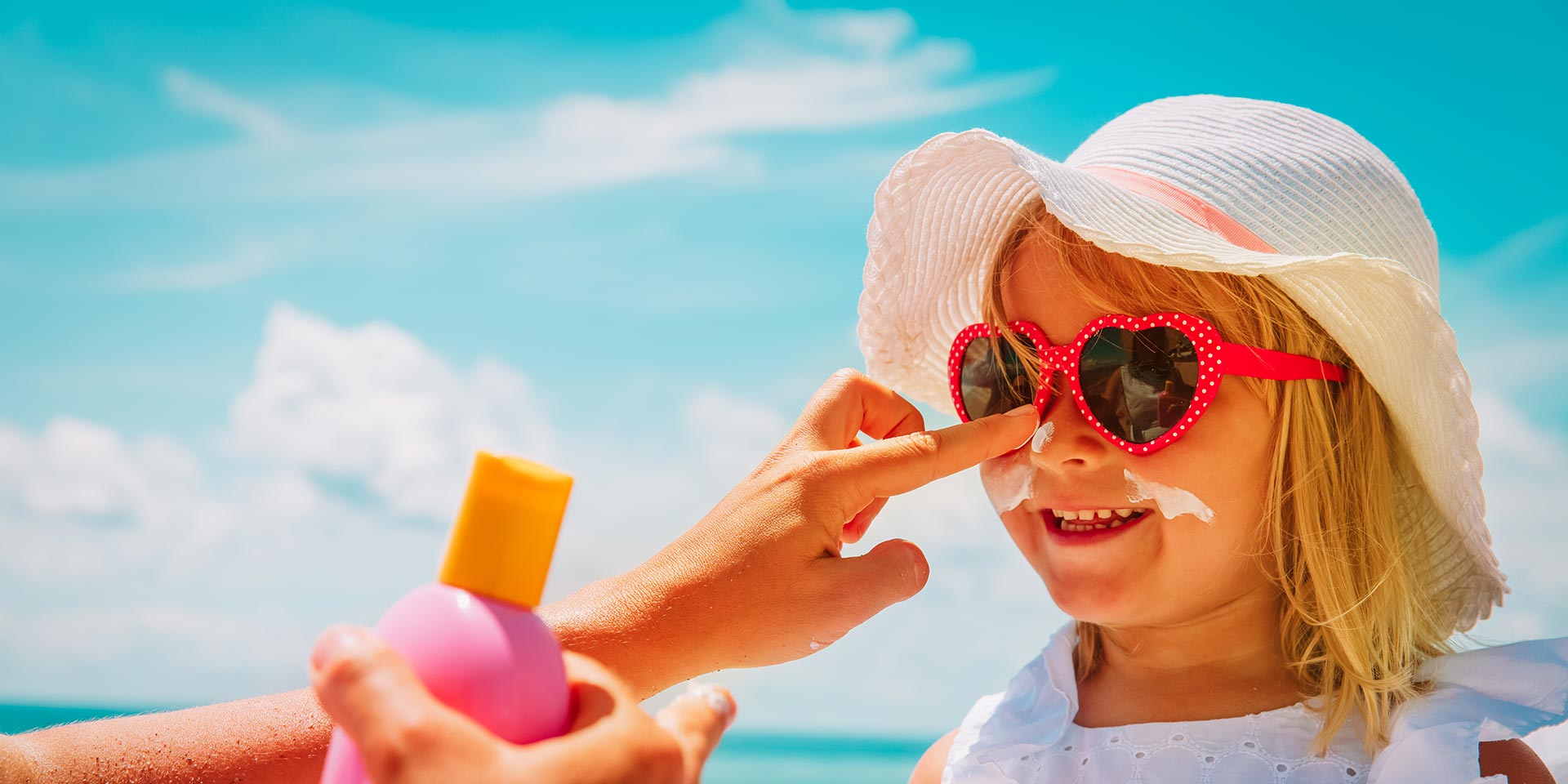 mutter trägt sonnencreme auf gesicht  kindes auf