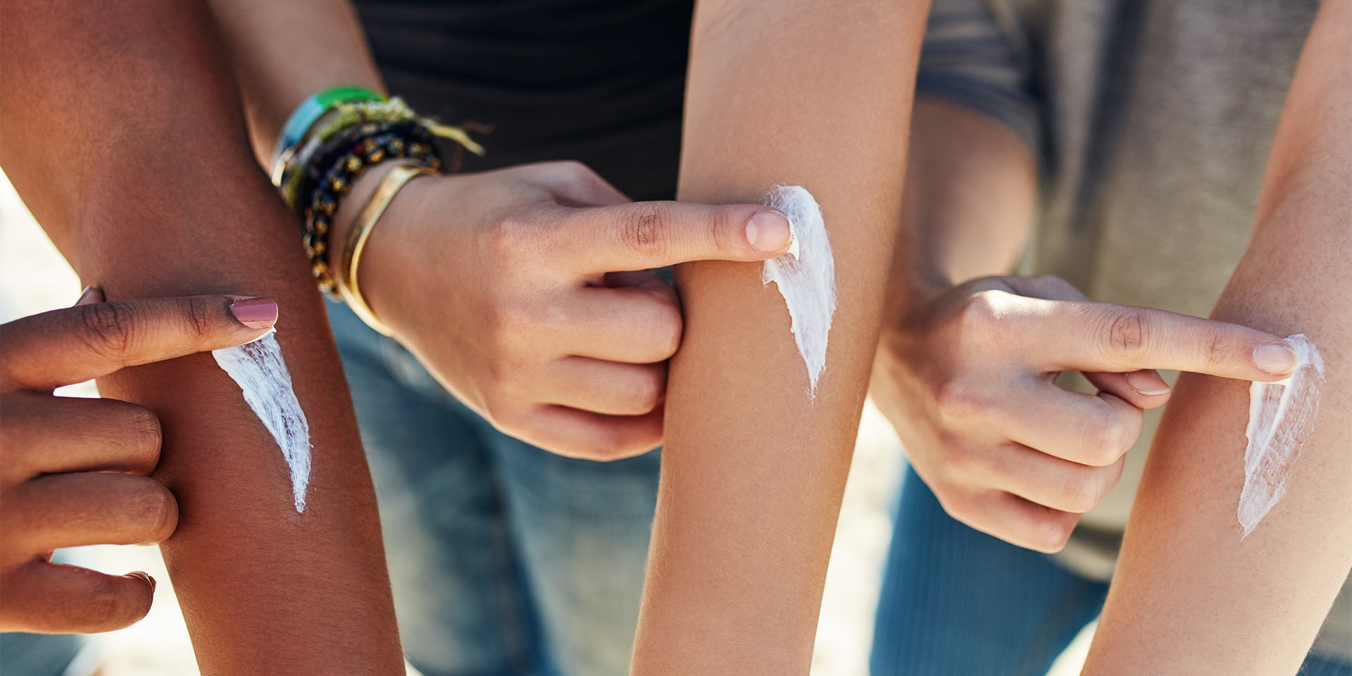 drei personen crfemen arme  sonnencreme ein