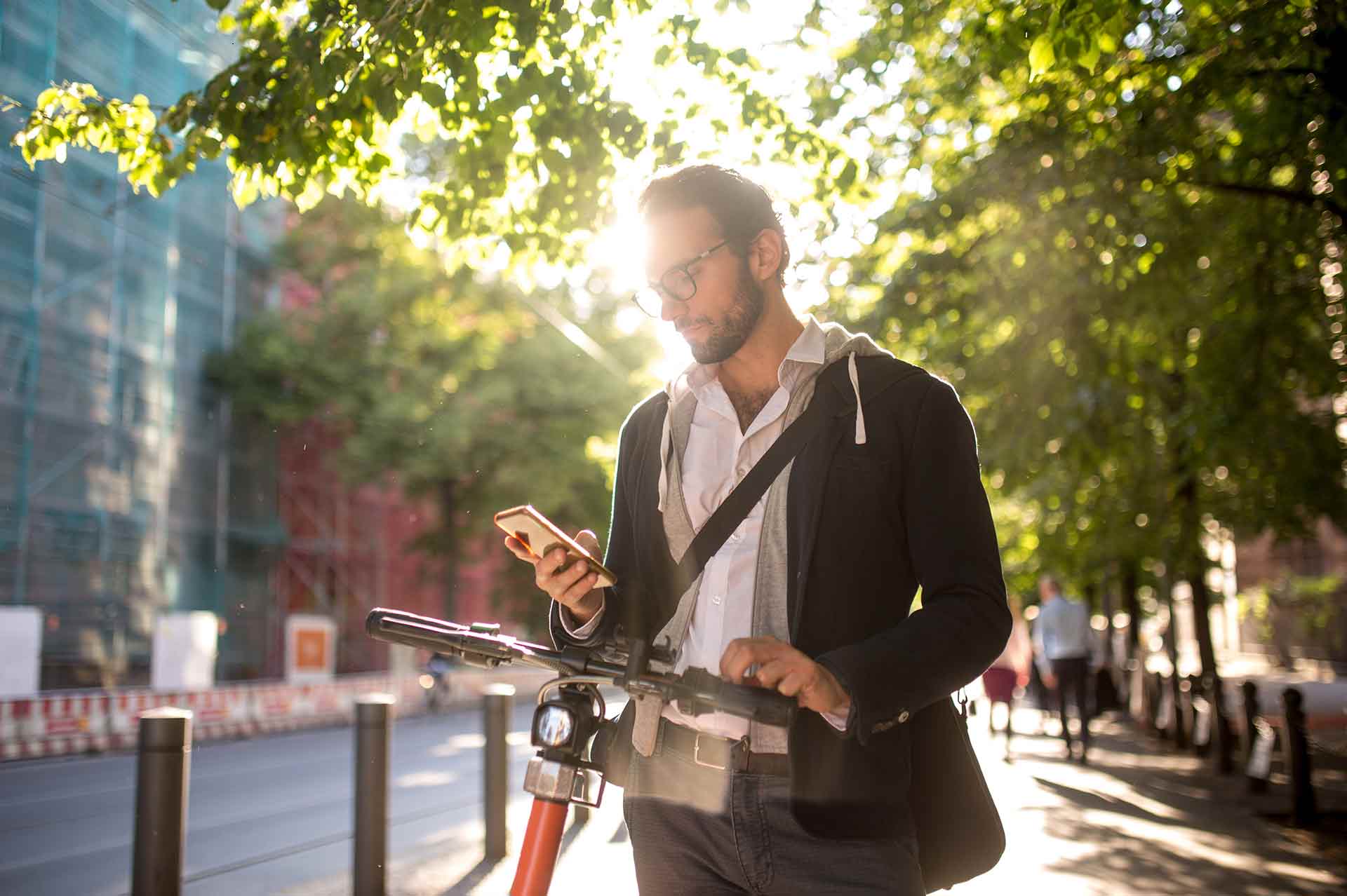 mobilität in städten mann auf scooter schaut aufs handy