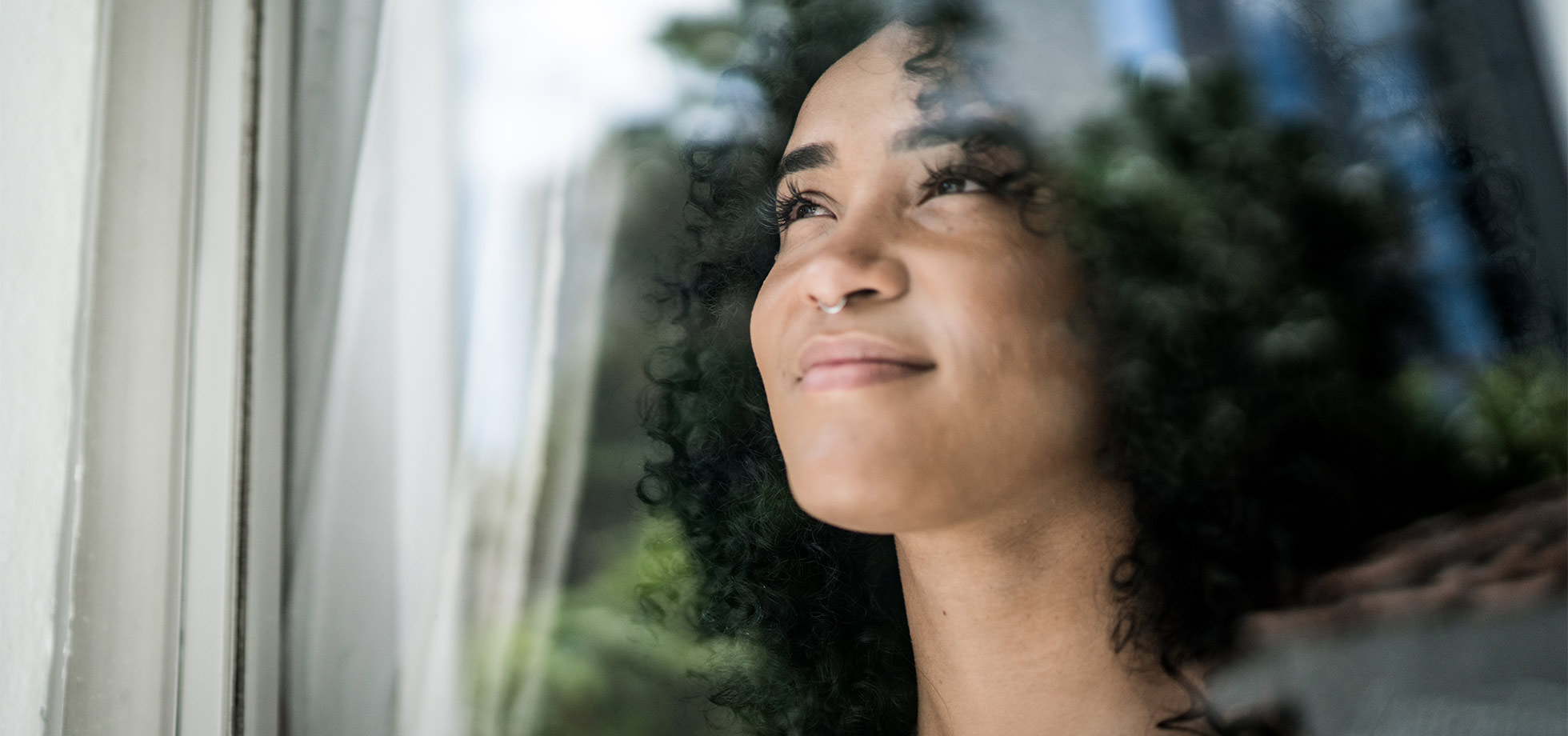 junge frau schaut durch fenster zu hause, coach