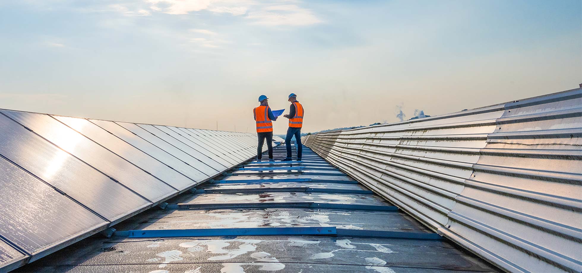 zwei techniker in  ferne diskutieren zwischen langen reihen von photovoltaik-modulen. energiezukunft