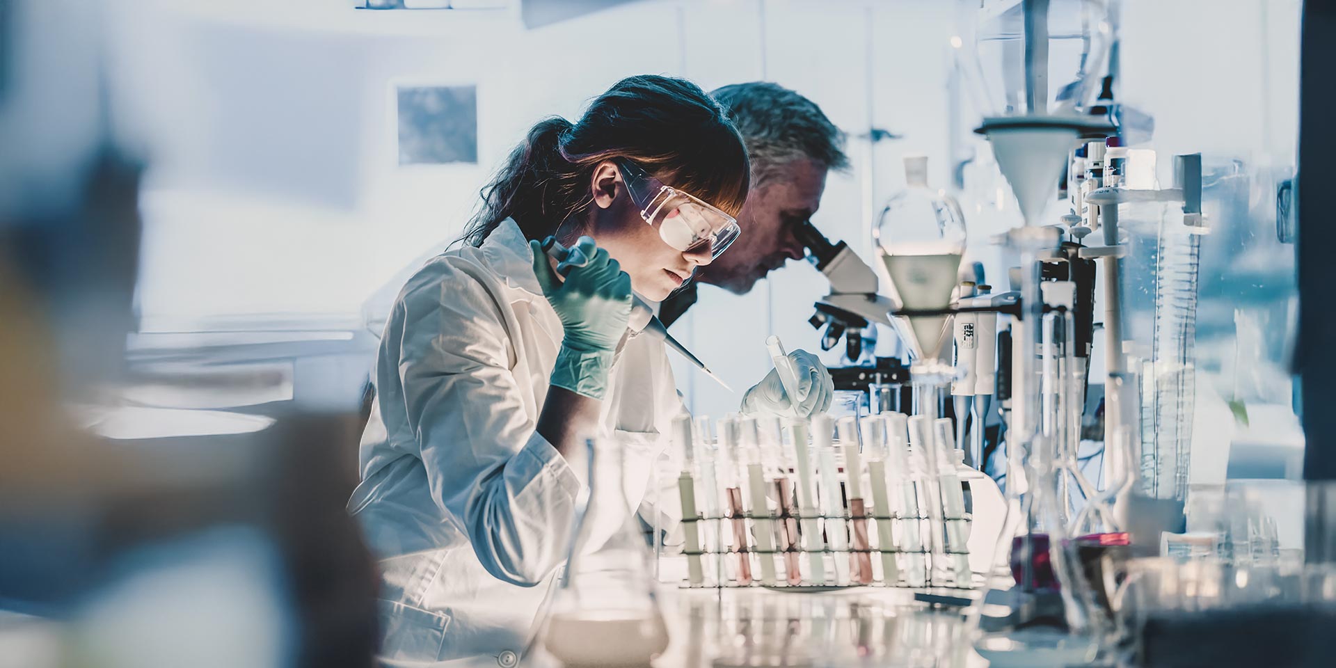 forscher des gesheitswesens arbeiten in einem biowissenschaftlichen labor. junge wissenschaftlerin  älterer männlicher vorgesetzter bei  vorbereitung  analyse von objektträgern im forschungslabor. interview  emma hodcroft  lavinia heisenberg