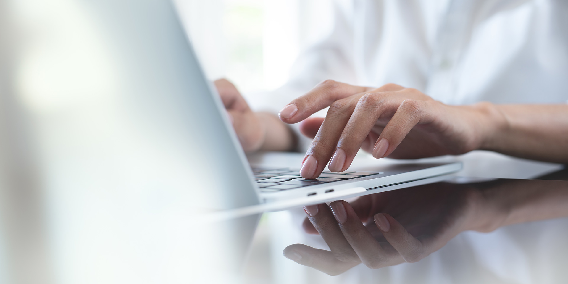 close up von business-frau hand tippen auf laptop-computer-tastatur  reflexion auf digitale tablette auf bürotisch, online-arbeiten, surfen im internet, fern job, remote-arbeit-konzept. symbolbild finanzielle unabhängigkeit