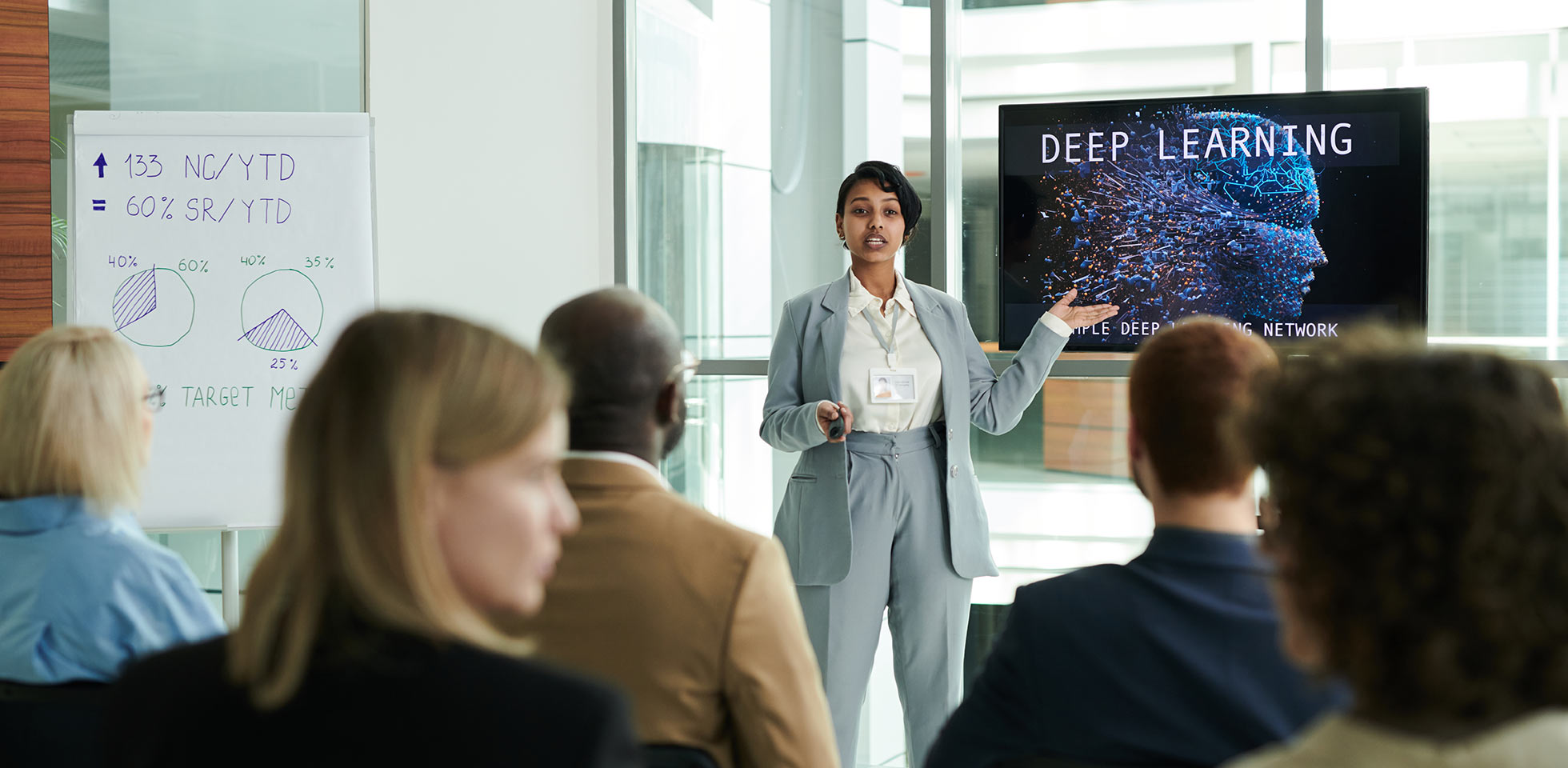 selbstbewusste junge geschäftsfrau im eleganten anzug bei  präsentation eines deep-learning-kurses auf einer ki-messe, während sie auf einem seminar vor dem publikum steht