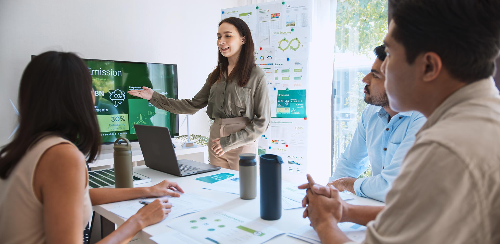 eine asiatische frau leitet eine junge gruppe multiethnischer geschäftsleute in einer teamsitzung,  einen laptop für eine präsentation zum thema esg auf einem monitor verwenden. nachhaltige unternehmenspraxis, konzept "menschen arbeiten zu hause. symbolbild gen z bei  arbeit