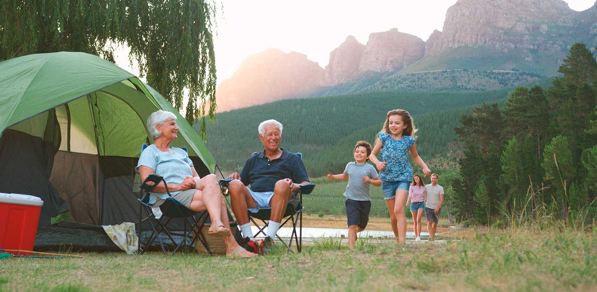 multi-generationen-familie auf camping-reise in  landschaft am see entspannen,  kin spielen. symbolbild familienreisen