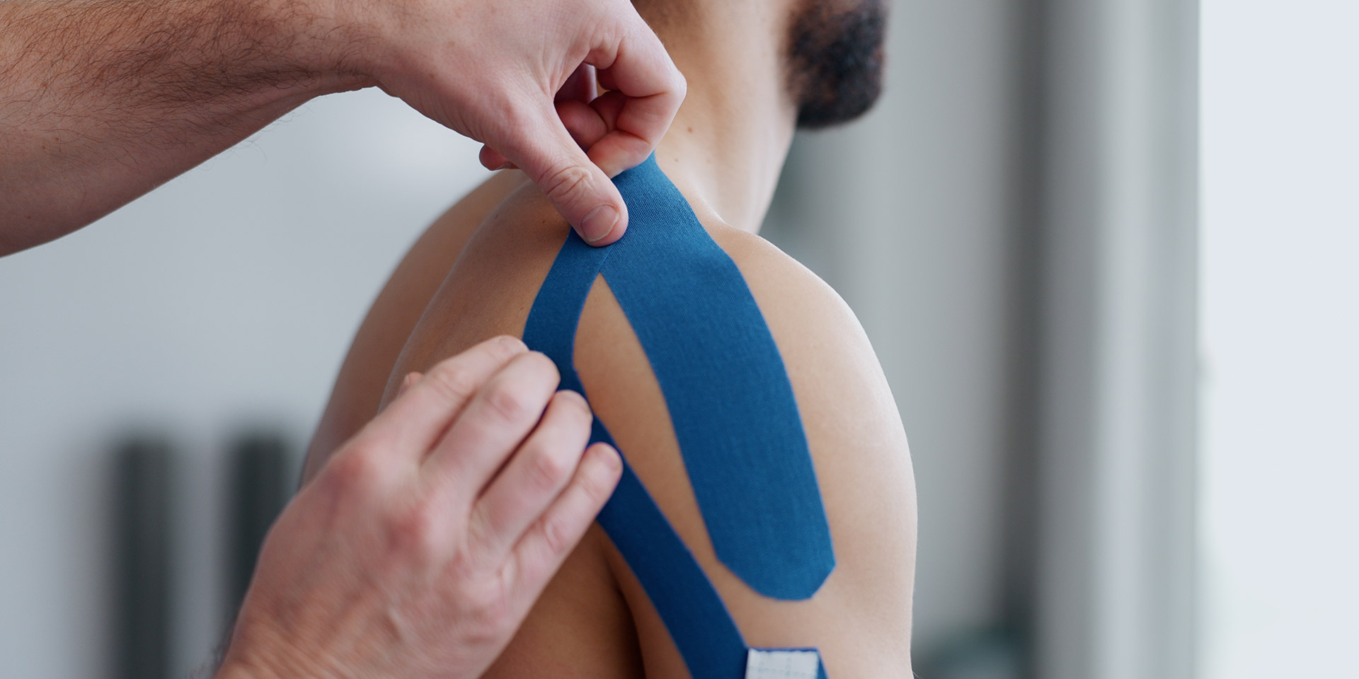 physiotherapist, patient and hands with tape for recovery, injury and guide for health at clinic. people, help and support with application for shoul pain with muscle in rehabilitation at hospital