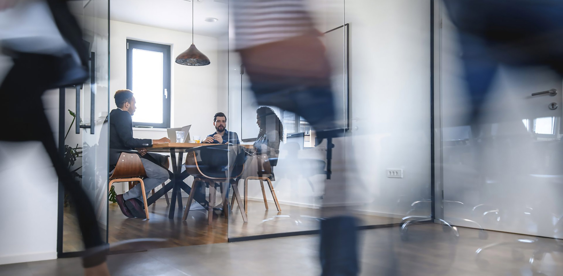 verschmmene bewegung von kollegen,  zügig den büroflur entlanggehen, während ane kollegen im konferenzraum sitzen  ideen diskutieren. symbolbild digitale souveränität