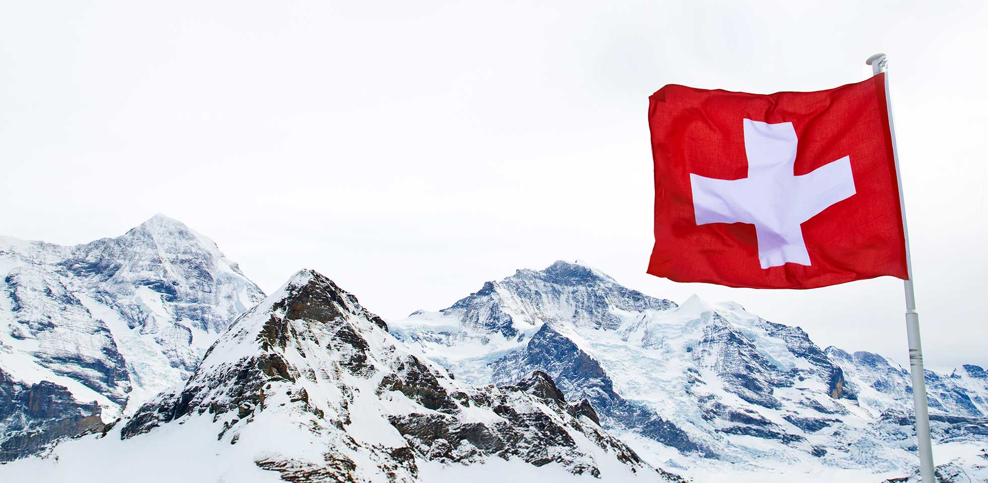 die schweizer fahne weht vor den alpen. symbolbild opting-out bei überschuldung o kapitalverlust