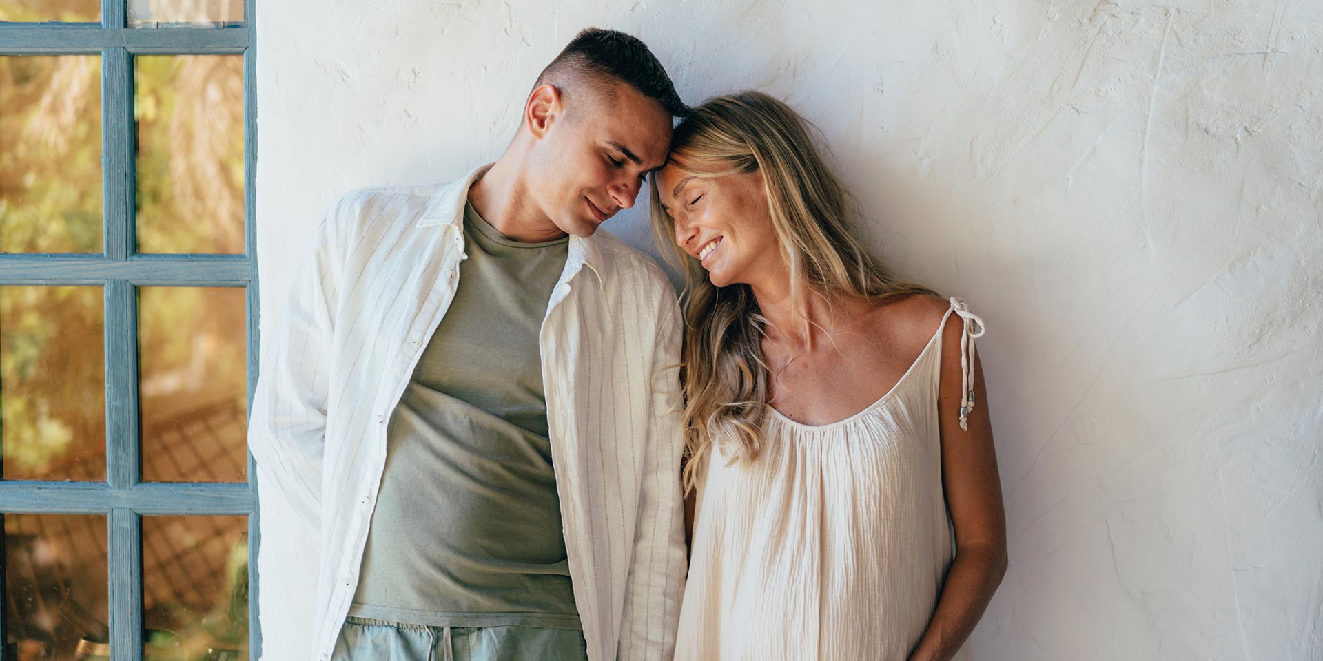 couple in love standing near the wall. a pregnant man holds her husband's hand