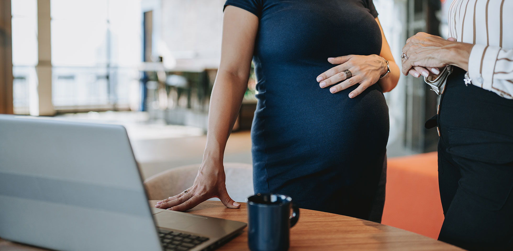 schwangere geschäftsfrau im gespräch  einem kollegen. symbolbild familienplanung