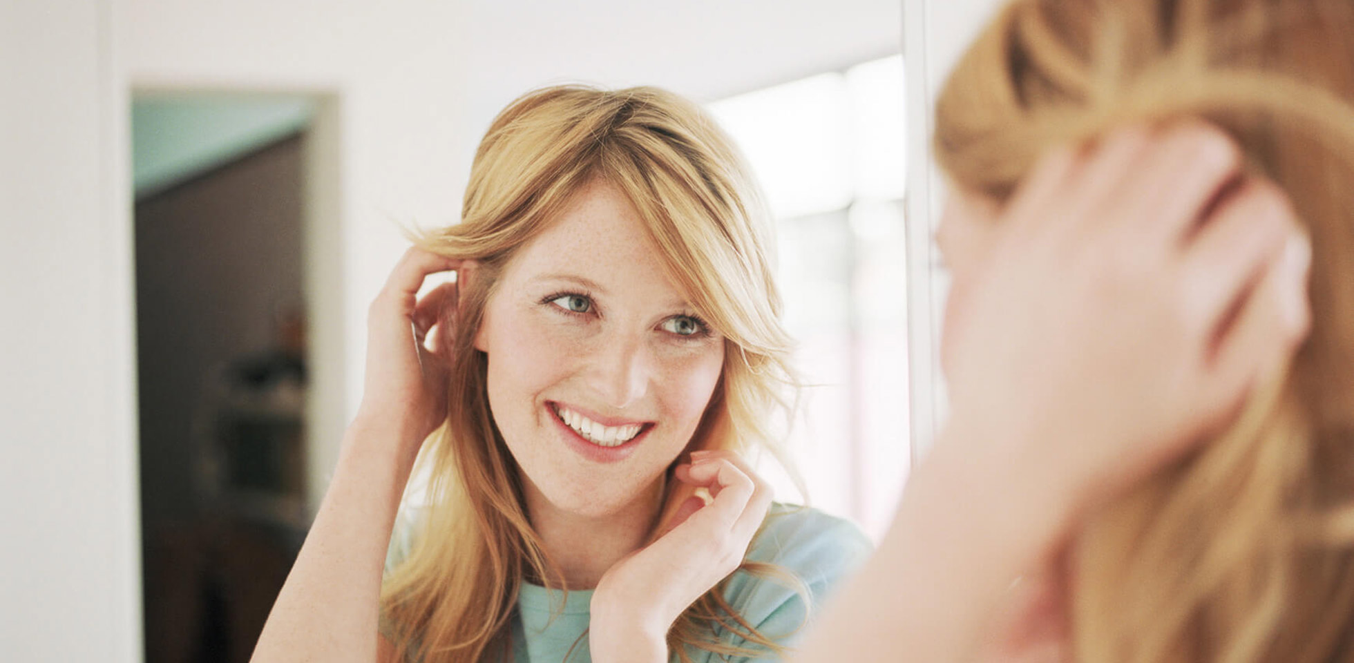 frau betrachtet sich im spiegel. symbolbild pms