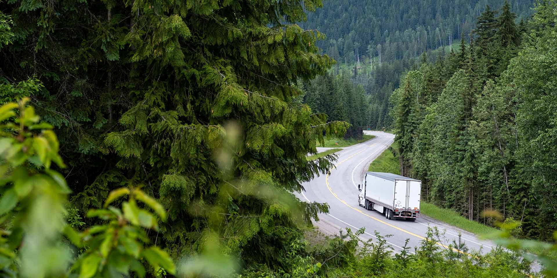 container-lkw entlang einer malerischen straße durch  kanadischen rockies, dekarbonisierung