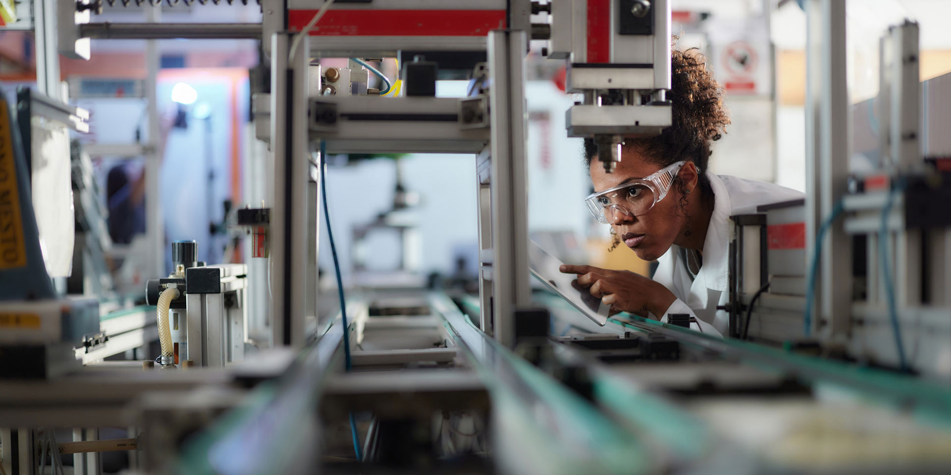 african american female scientist using digital tablet while rking on production line in laboratory, automatisierung