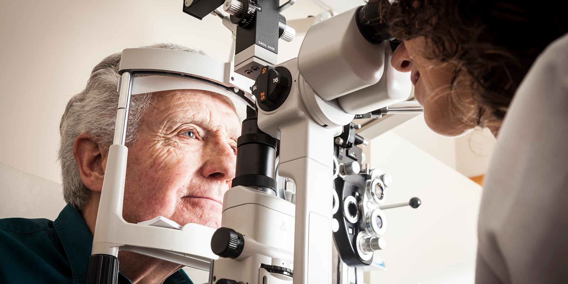 optometrist giving eye exam to senior patient, augen