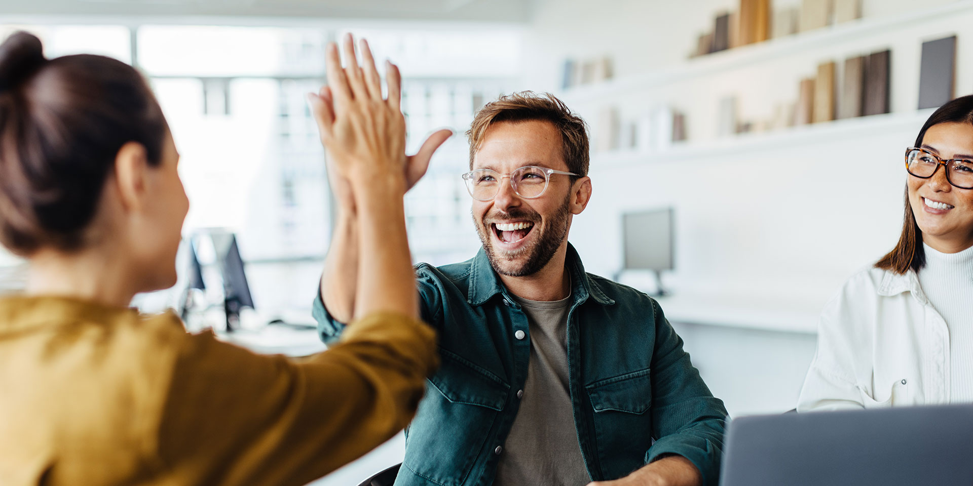 successful business people giving each other a high five in a meeting. t young business professionals celebrating teamrk in an office. leben