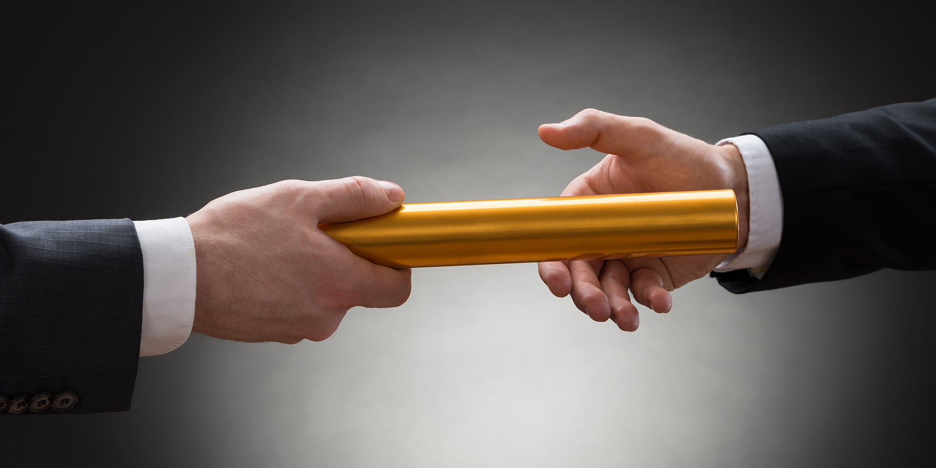 close-up of t businessman's hand passing a golden relay baton, nachlassplanung